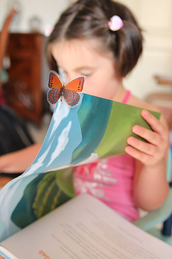 Young girl reading book with butterfly on page