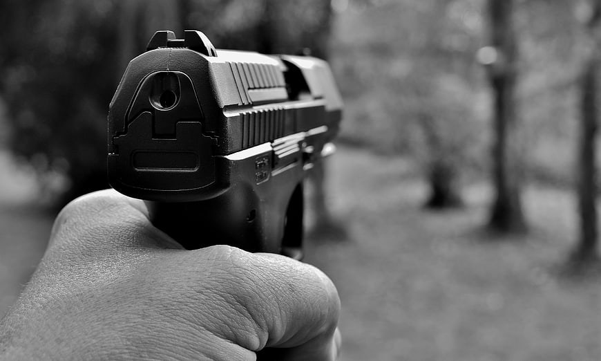 Hand holding pistol in black and white outdoor setting