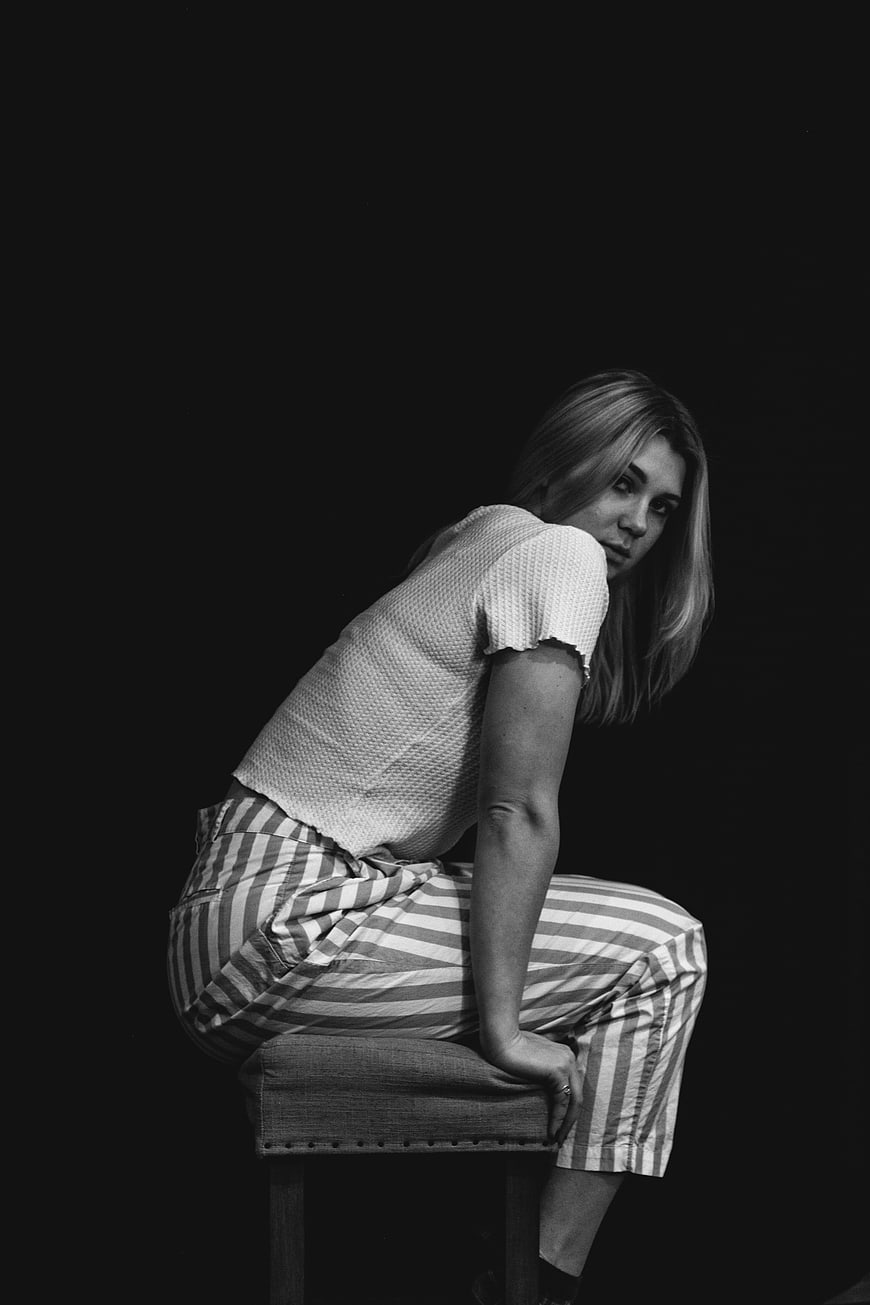 Black and white portrait of stylish woman sitting on stool