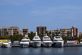 Luxury yachts docked in Barcelona harbor with city skyline