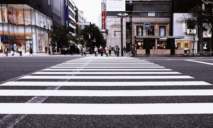 Wide pedestrian crossing on a busy Japanese city street with pedestrians