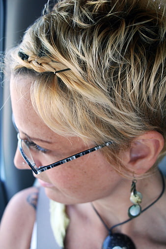 Close-up profile of blonde woman with braided updo and glasses