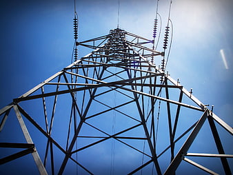 Low angle view of steel electricity pylon against blue sky