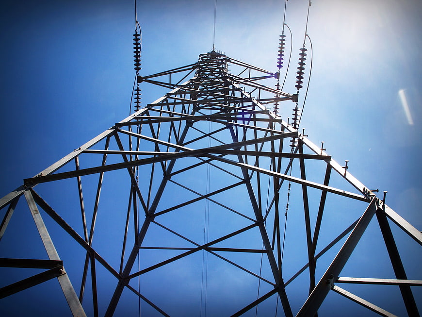 Low angle view of steel electricity pylon against blue sky
