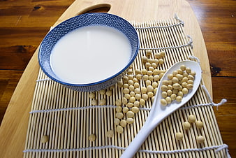 Bowl of soy milk with soybeans on bamboo mat
