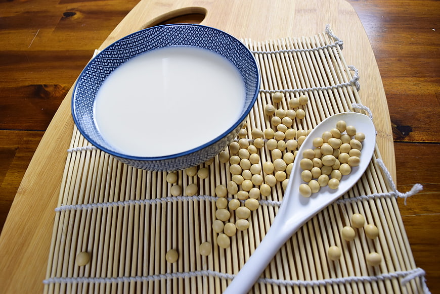 Bowl of soy milk with soybeans on bamboo mat