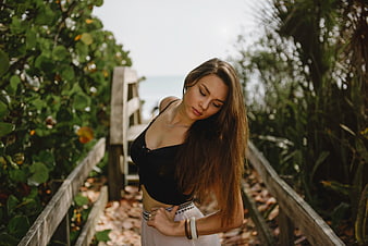 Woman in black top on wooden boardwalk near beach