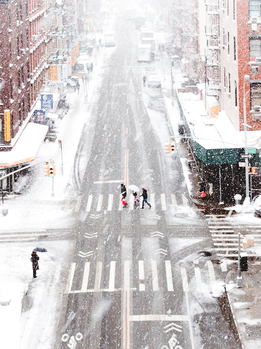 High angle view of snowy city street with pedestrians crossing