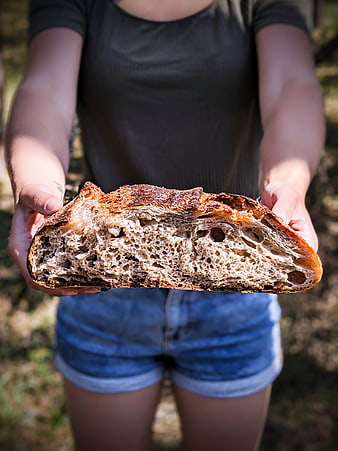 Woman holding fresh artisan sourdough bread outdoors