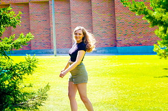 Happy woman walking on grass in front of brick building