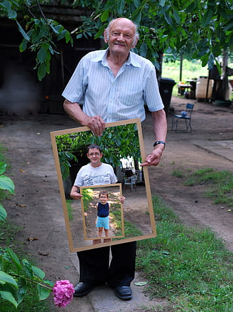 Grandfather holding framed photos of son and grandson generations