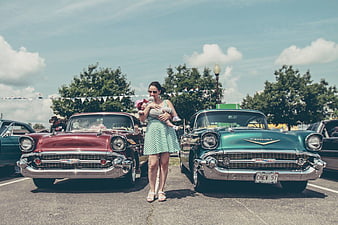 Mother Holding Baby Between Two Classic 1957 Chevrolet Cars