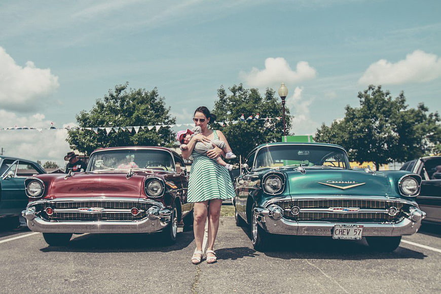Mother Holding Baby Between Two Classic 1957 Chevrolet Cars