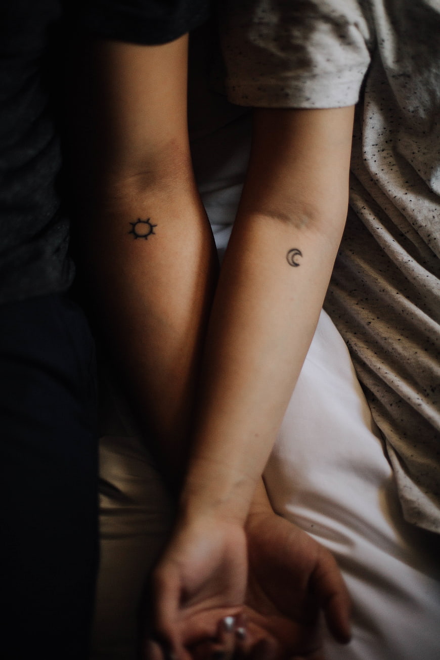 Couple with matching sun and moon tattoos on arms