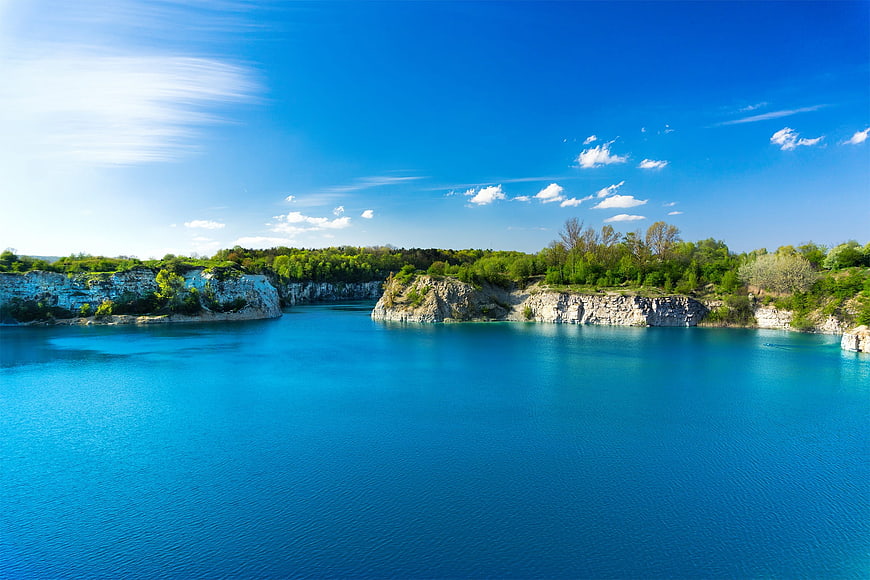 Turquoise quarry lake with white cliffs and blue sky