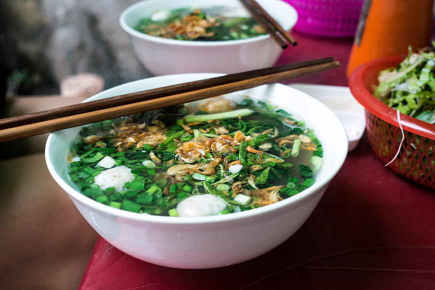 Close-up of Vietnamese noodle soup with meatballs and herbs