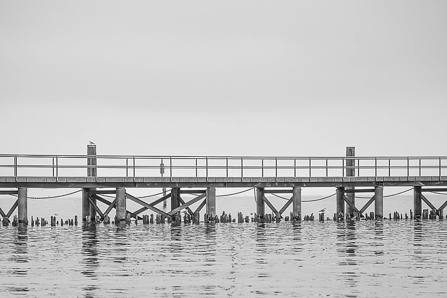 Black and white wooden pier extending over calm water