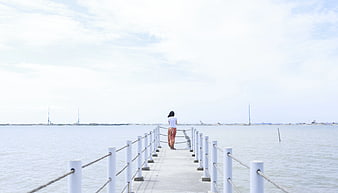 Woman Standing on Pier Looking at Ocean