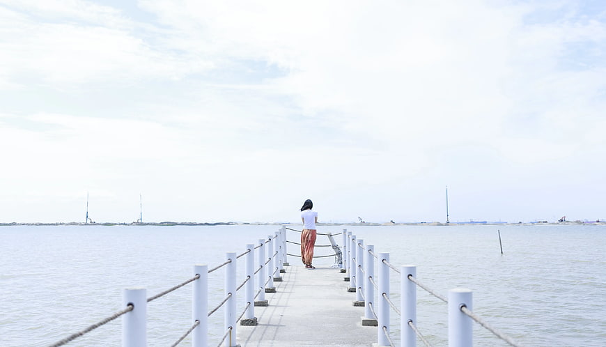 Woman Standing on Pier Looking at Ocean