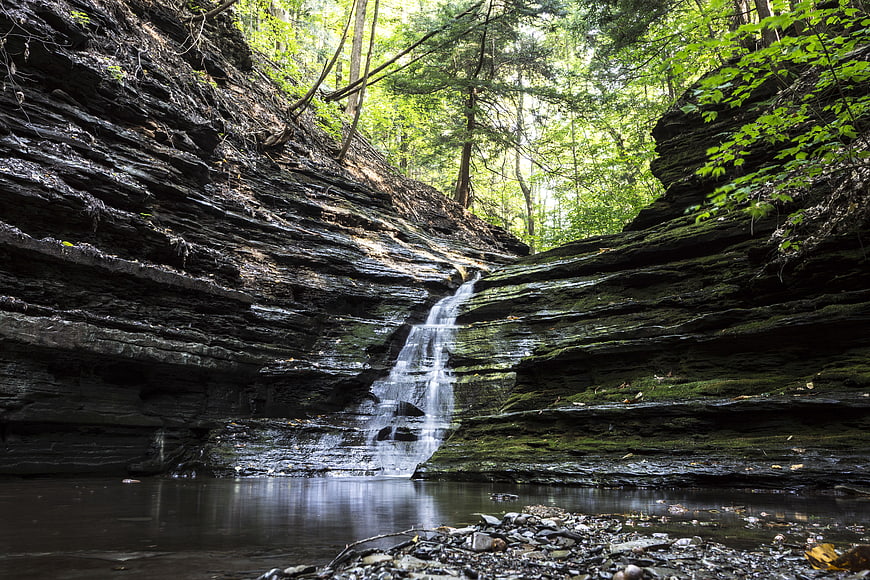 Small waterfall cascading down layered rocks in a lush forest