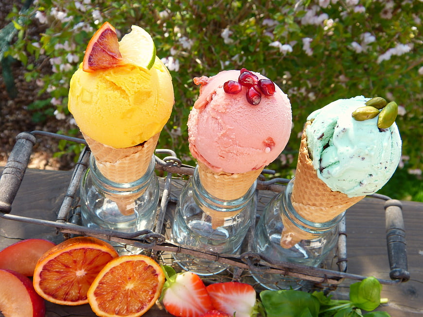 Three colorful fruit sorbets in cones with fresh garnishes