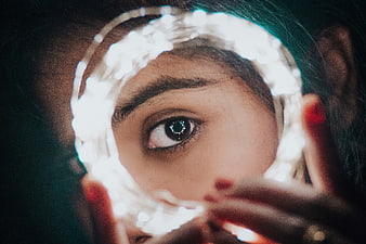 Close-up of woman's eye framed by glowing fairy lights