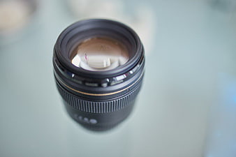 Close-up of black camera lens on glass surface