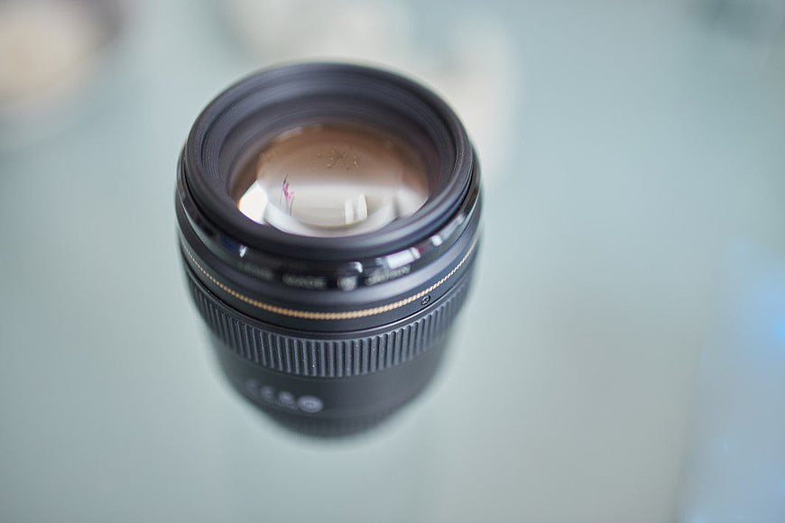 Close-up of black camera lens on glass surface