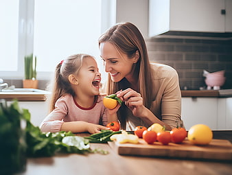Happy mother and daughter laughing with fresh vegetables in kitchen