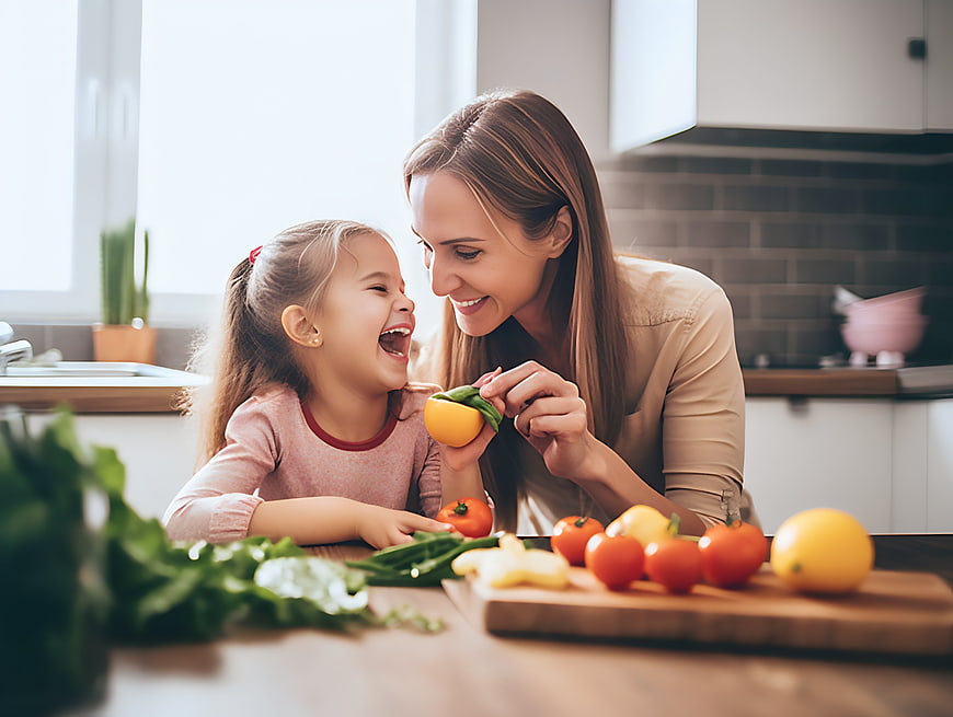 Happy mother and daughter laughing with fresh vegetables in kitchen