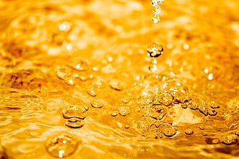 Golden liquid splash with bubbles and ripples macro shot