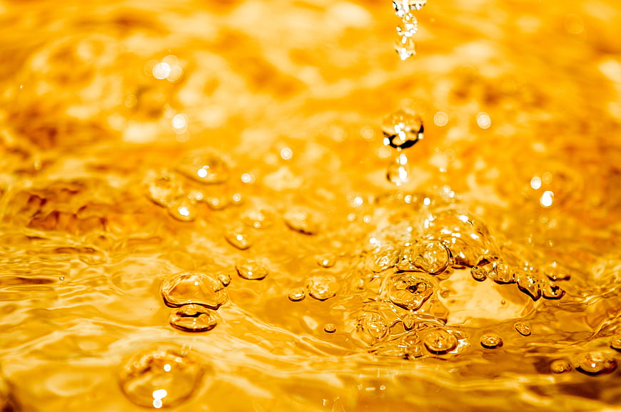 Golden liquid splash with bubbles and ripples macro shot