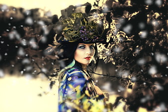 Woman in ornate floral hat with dramatic makeup in forest