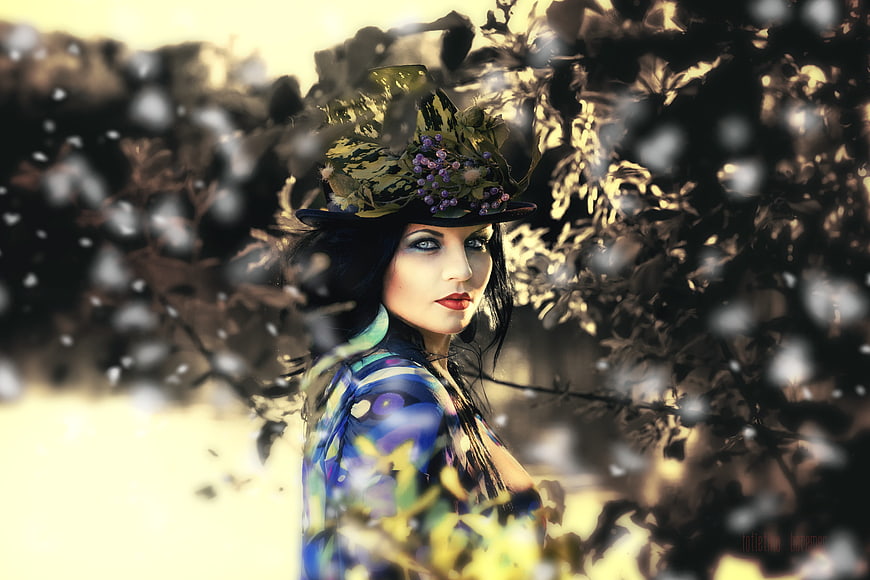 Woman in ornate floral hat with dramatic makeup in forest