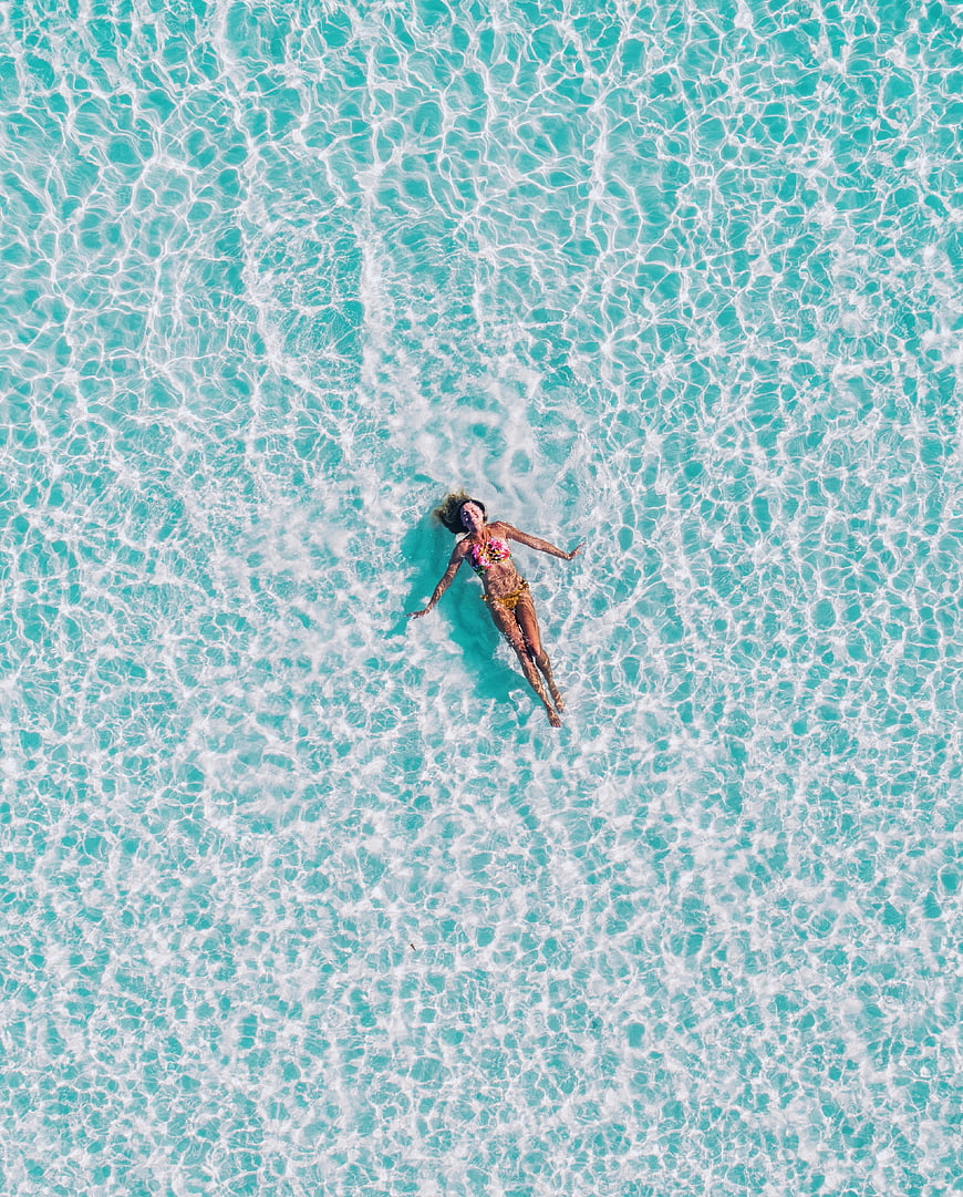 Aerial view of woman floating in turquoise ocean water