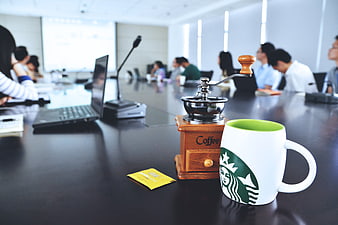 Coffee Mug and Grinder on Conference Table with Blurred Meeting Background
