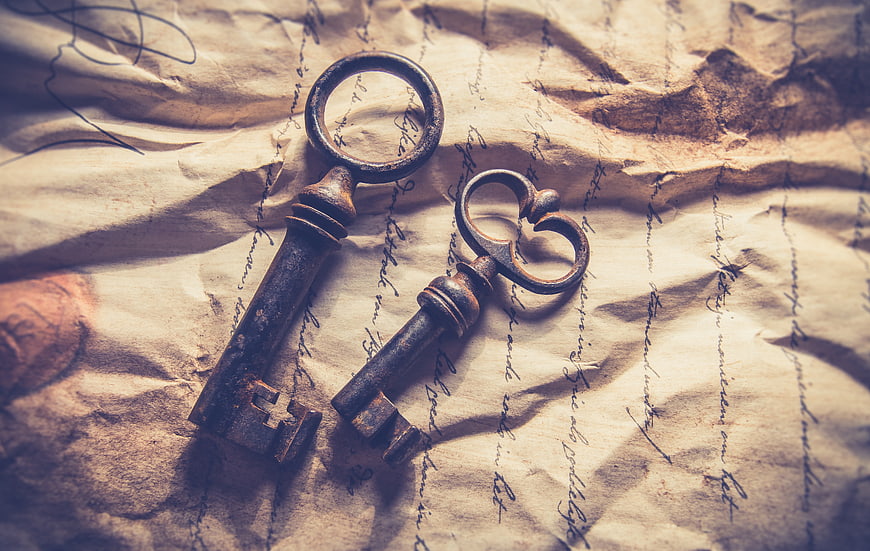 Antique rusty keys on old handwritten crumpled paper