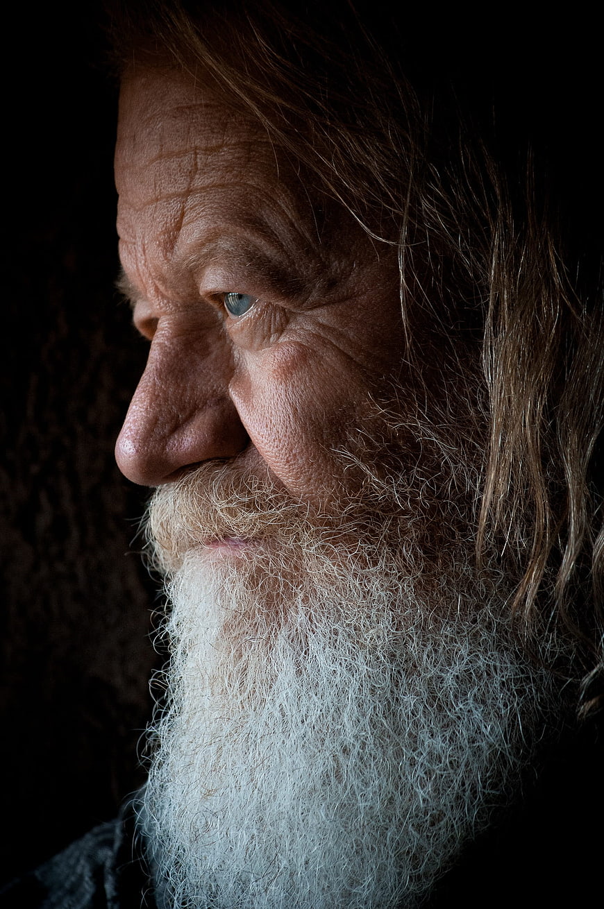 Close-up profile portrait of elderly man with long white beard