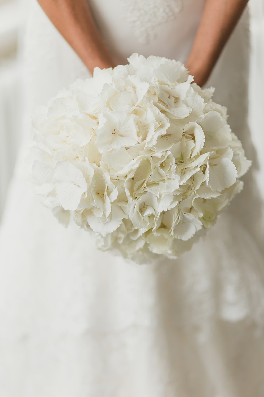 Close-up of white hydrangea wedding bouquet held by bride