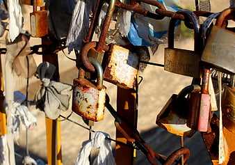 Rusty padlocks and fabric amulets on a fence