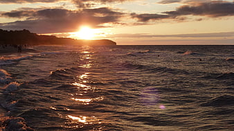 Golden Sunset Over Ocean Waves with Silhouetted Coastline