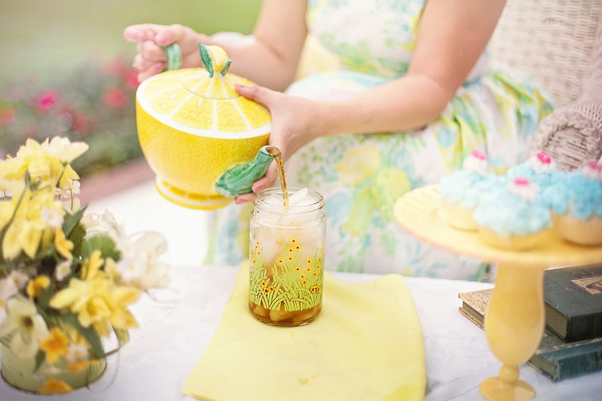 Woman Pouring Tea from Lemon Shaped Teapot at Garden Party