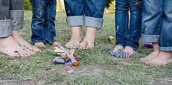 Bare feet with paint splatters on grass with brushes