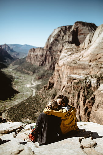 Couple embracing on cliff edge overlooking canyon landscape