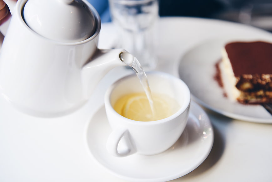 Pouring hot tea with lemon into white cup