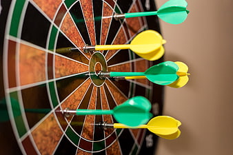 Close-up of colorful darts hitting a magnetic dartboard