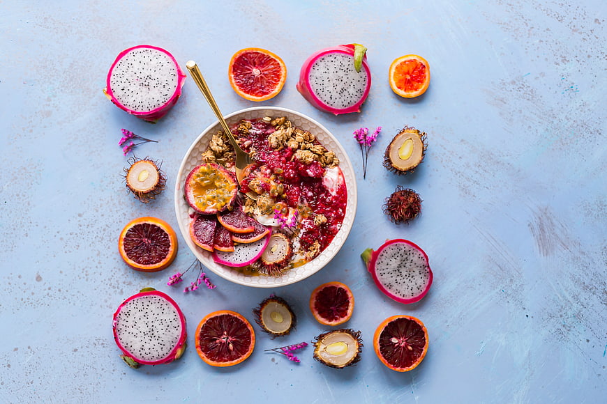 Overhead view of vibrant acai bowl with dragon fruit and blood orange