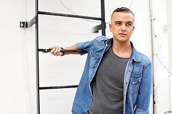 Young man in denim jacket leaning on metal ladder