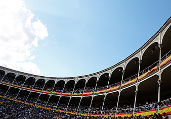 Crowded Spanish bullring stands under blue sky
