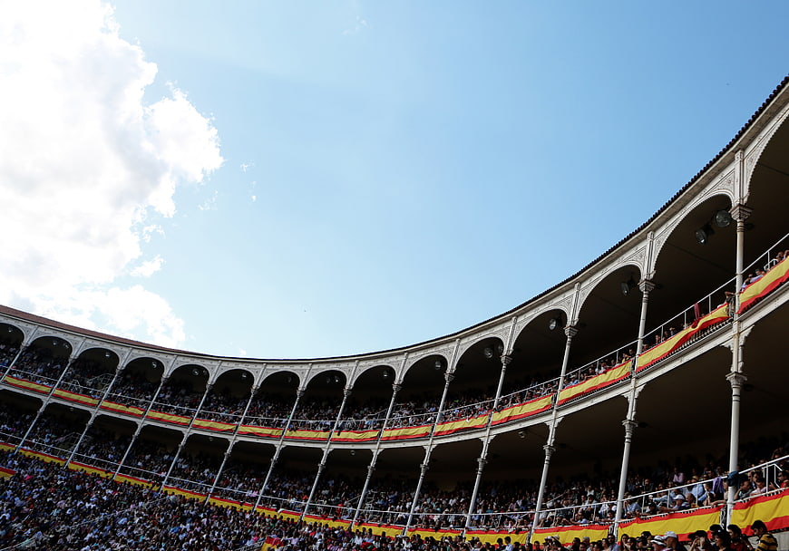 Crowded Spanish bullring stands under blue sky